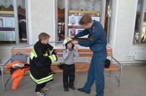 Пожарные одевают ребят в свое обмундирование