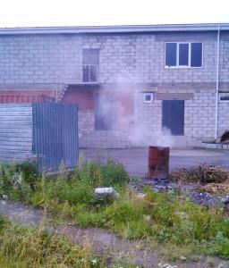Жгут мусор на задворках автомагазина
