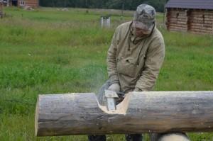 Константин Завьялов пилит пазы на бревнах для храма